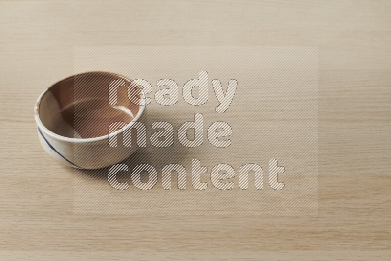 A multicolored pottery bowl on light wooden background