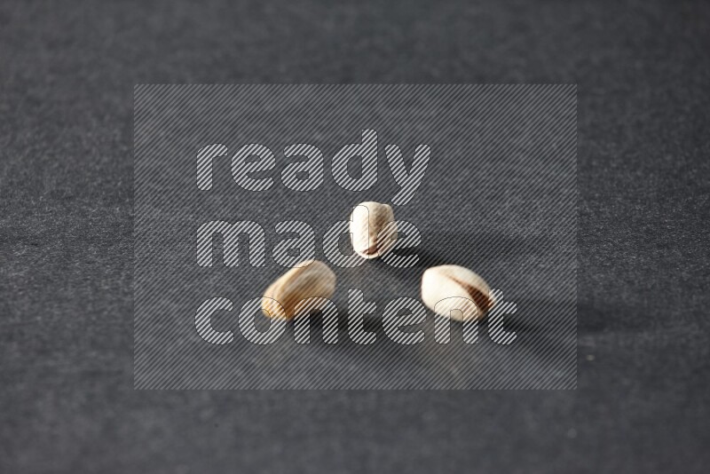 3 pistachios on a black background in different angles