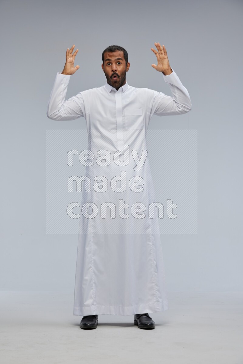 Saudi man Wearing Thob standing interacting with the camera on Gray background