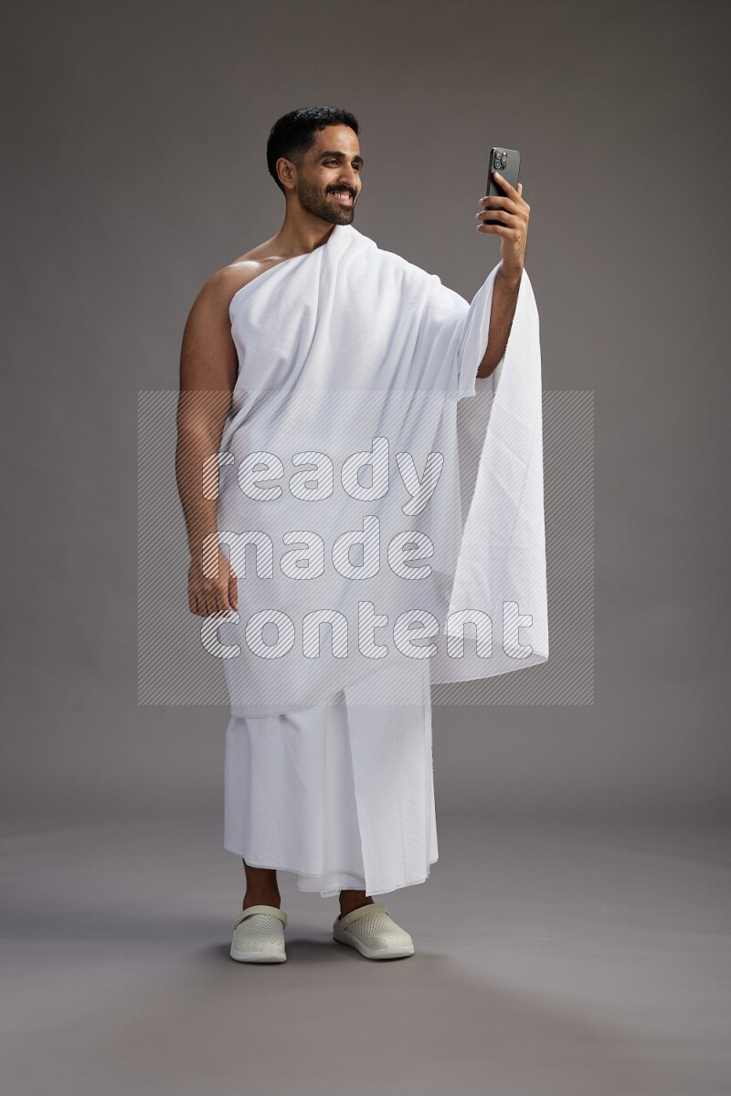 A man wearing Ehram Standing taking selfie on gray background