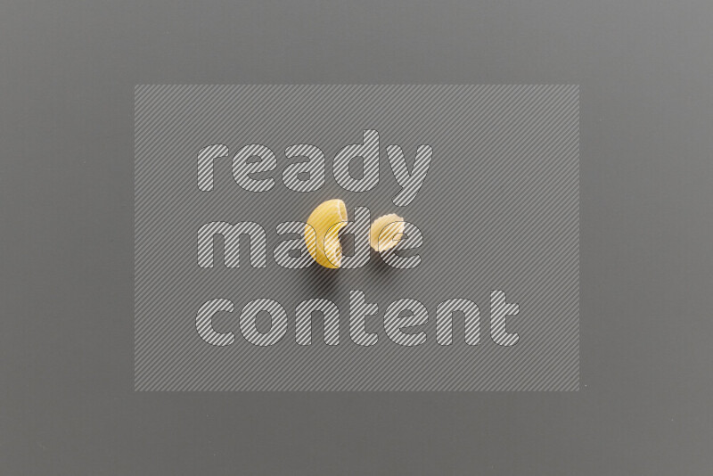 Elbow pasta with other types of pasta on grey background