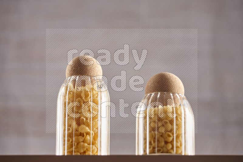 Raw pasta in glass jars on beige background