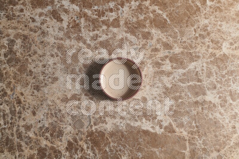 A beige pottery oven plate on beige marble background