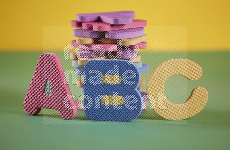 A set of colorful foam alphabet letters on yellow and green background (kids toys)