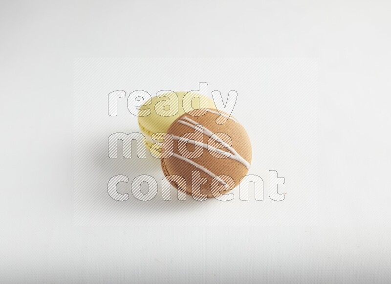 45º Shot of of two assorted Brown Irish Cream, and Yellow Lime macarons on white background