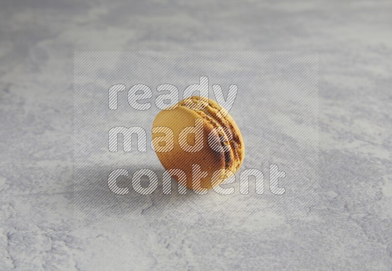 45º Shot of Yellow Crème Brulée macaron on white marble