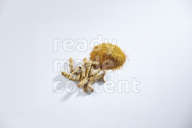 Turmeric powder and dried turmeric whole fingers on white flooring