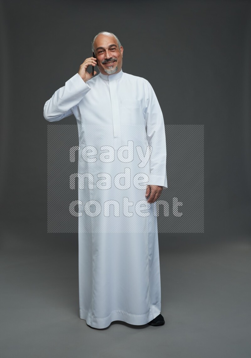 Saudi man without shomag Standing talking on phone on gray background