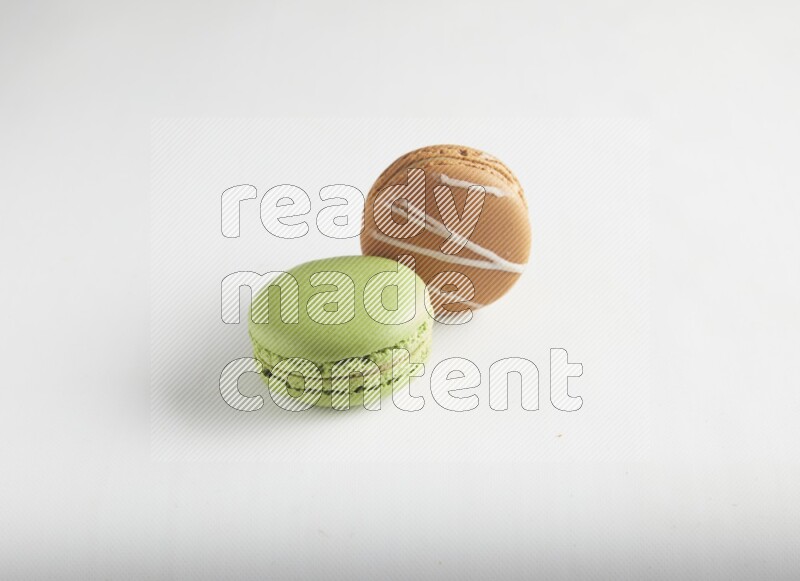 45º Shot of of two assorted Brown Irish Cream, and Green Pistachio macarons on white background