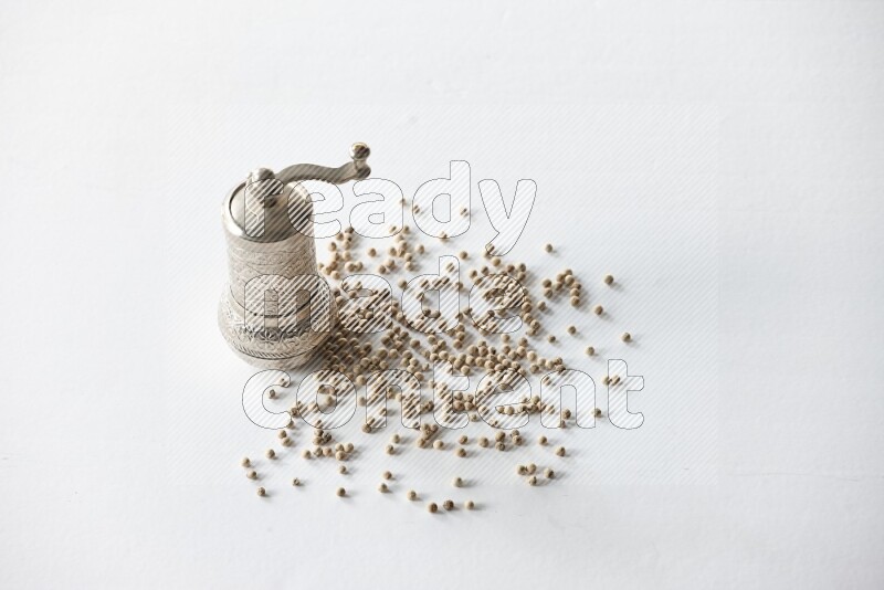 White pepper beads with a metal grinder on white flooring