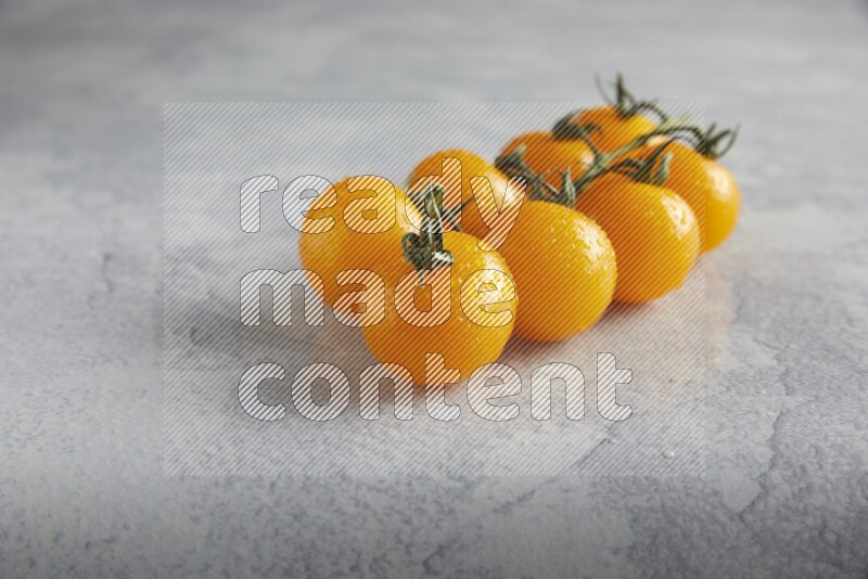 Yellow cherry tomato vein on a light grey textured background 45 degree