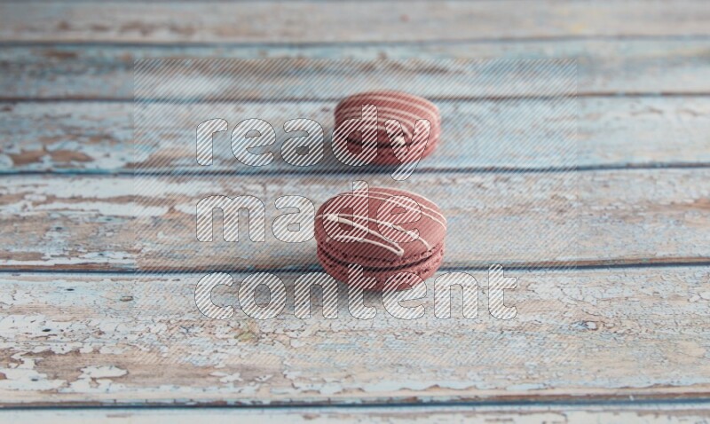 45º Shot of two Red Poppy Flower macarons on light blue wooden background