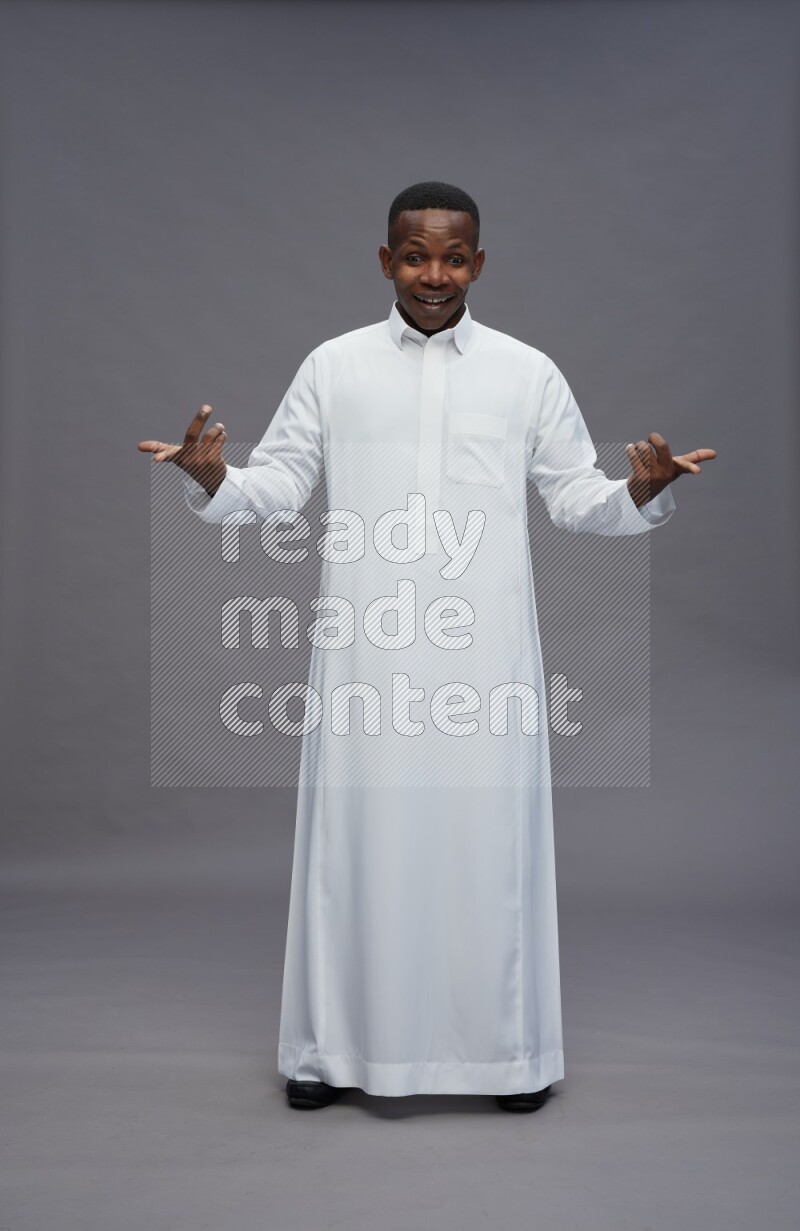 Saudi man wearing thob standing interacting with the camera on gray background