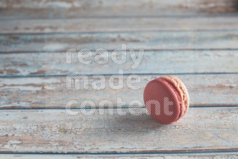 45º Shot of Pink Litchi Raspberry macaron on light blue wooden background