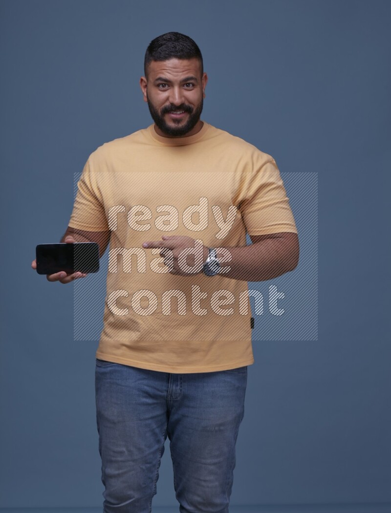 A man Playing Games on Smartphone on Blue Background wearing Orange T-shirt