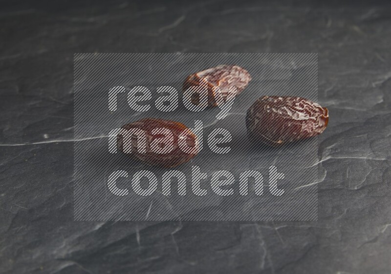three madjoul dates on a black textured background