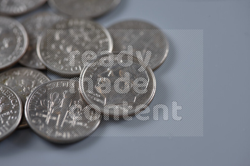 A close-up of scattered United States one dime coins on grey background