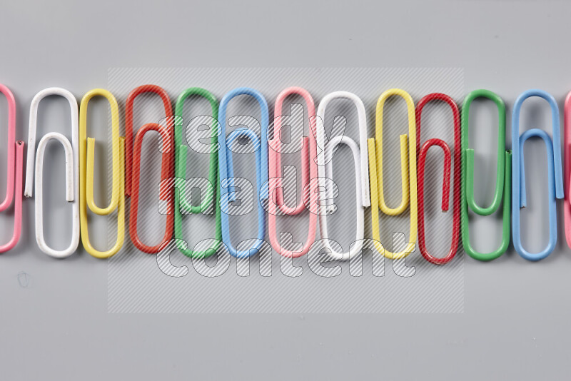 Multicolored paper clips isolated on a grey background