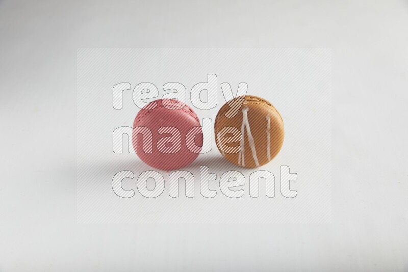 45º Shot of of two assorted Brown Irish Cream, and Pink Raspberry macarons on white background