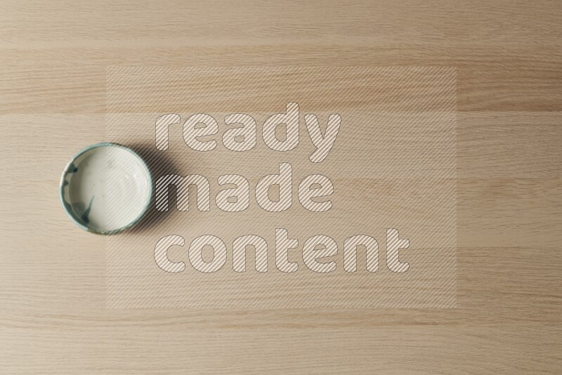 وعاء فخاري متعدد الألوان على خلفية خشبية فاتحة