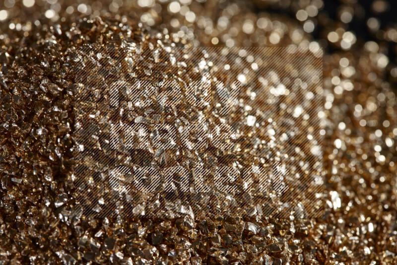 Gold shimmering fragments of glass scattered on a black background