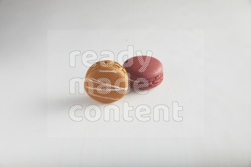 45º Shot of of two assorted Brown Irish Cream, and Red Velvet macarons on white background