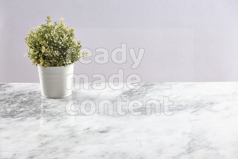 Artificial plant in white pot on grey marble background