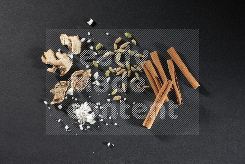 الزنجبيل والملح والهيل وأعواد القرفة على خلفية سوداء