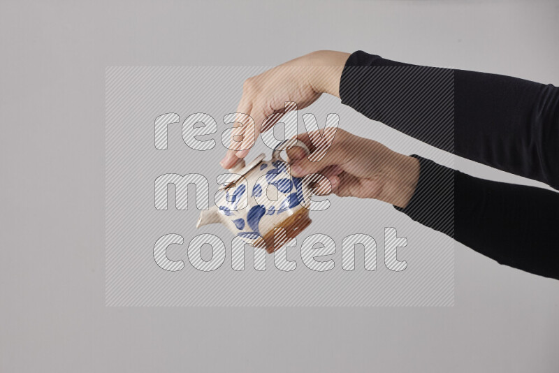 A woman in black abaya holding different pottery essentials in different positions
