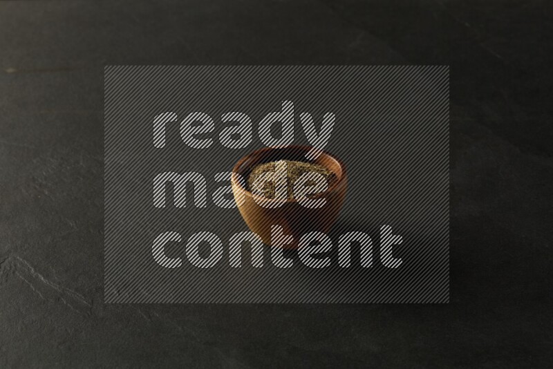 wooden round sauce bowl filled with herbs on grey textured countertop