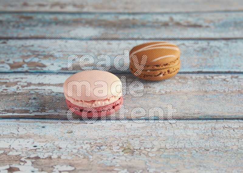 45º Shot of of two assorted Brown Irish Cream, and Pink Litchi Raspberry macarons on light blue background