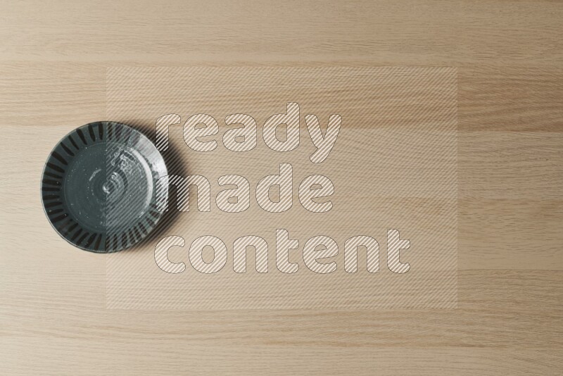 صحن فخاري أخضر داكن على خلفية خشبية فاتحة