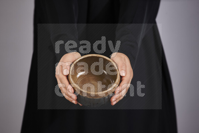 A woman in black abaya holding different pottery essentials in different positions
