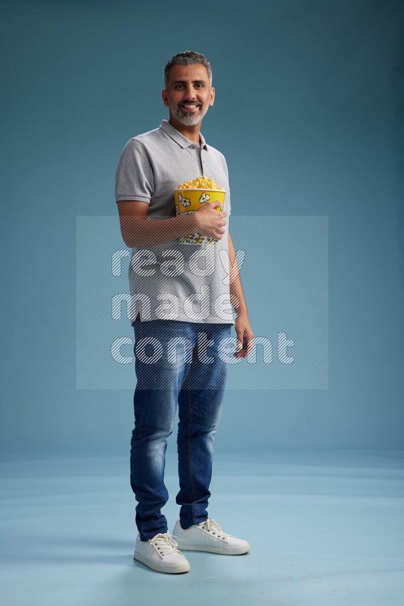 Man Standing eating popcorn on blue background