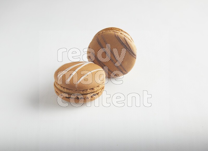 45º Shot of of two assorted Brown Irish Cream, and light brown  Almond Cream macarons on white background