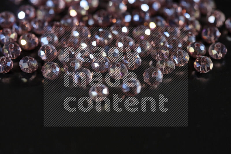 Rose transparent crystal beads scattered on a black background
