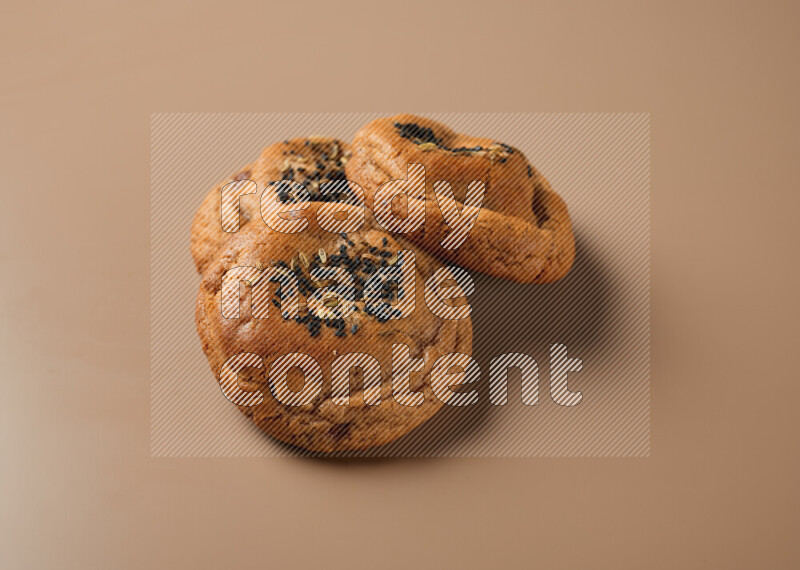 Hasawi cookies field with date and decorated by black seed and Anise grain on a brown background