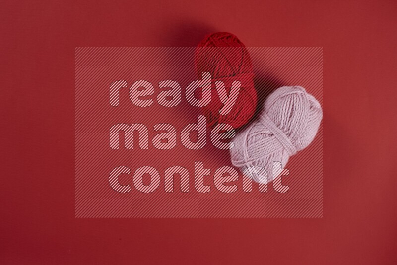 A pink and red collection of sewing and tailoring tools arranged on a red background