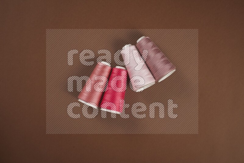 A pink collection of sewing and tailoring tools arranged on a brown background