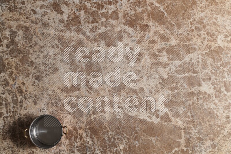 A small copper pot on beige marble background