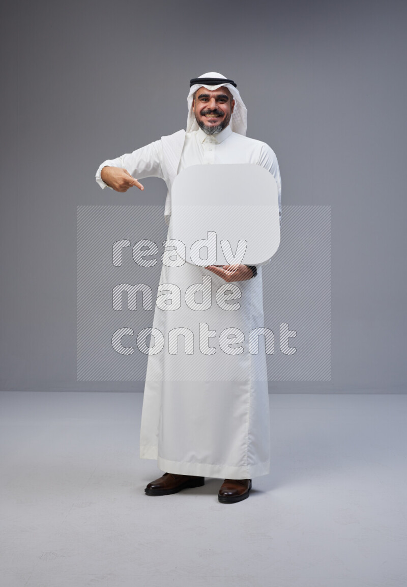 Saudi man Wearing Thob and white Shomag standing holding social media sign on Gray background