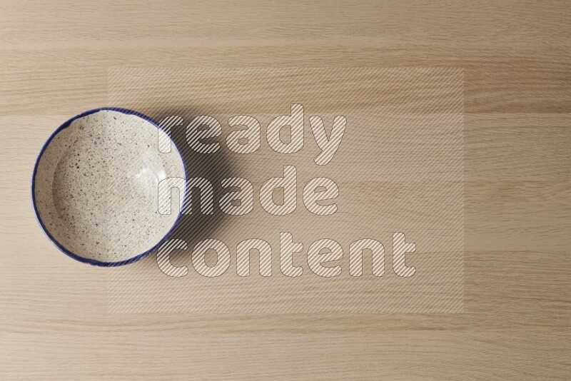 A multicolored pottery bowl on light wooden background