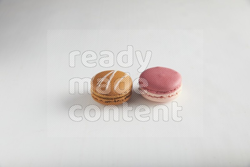45º Shot of of two assorted Brown Irish Cream, and Pink Litchi Raspberry macarons on white background