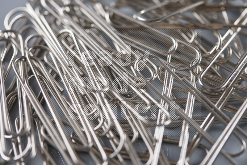 Silver paper clips isolated on a grey background
