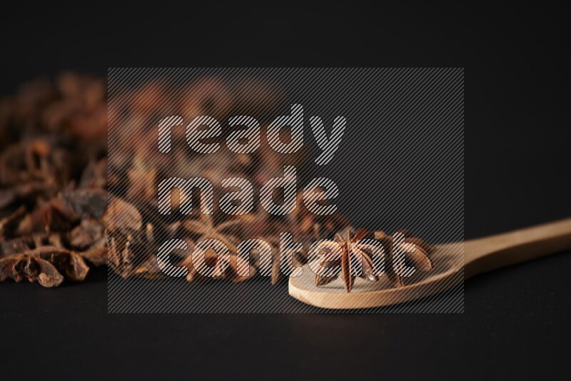 Star Anise in a wooden spoon and spreading on a black flooring