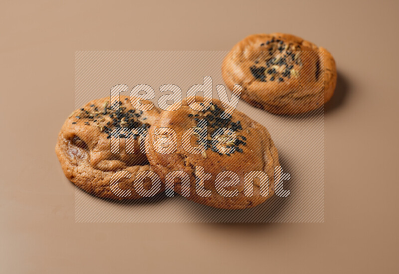 Hasawi cookies field with date and decorated by black seed and Anise grain on a brown background