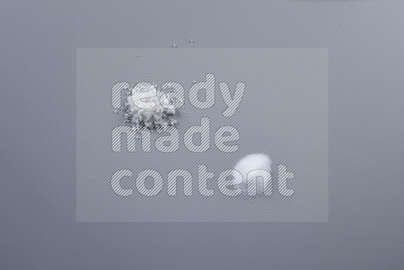 حفن من ملح الطعام، وملح البحر الخشن، وملح الهيمالايا الناعم، وملح الهيمالايا الخشن على خلفية رمادية