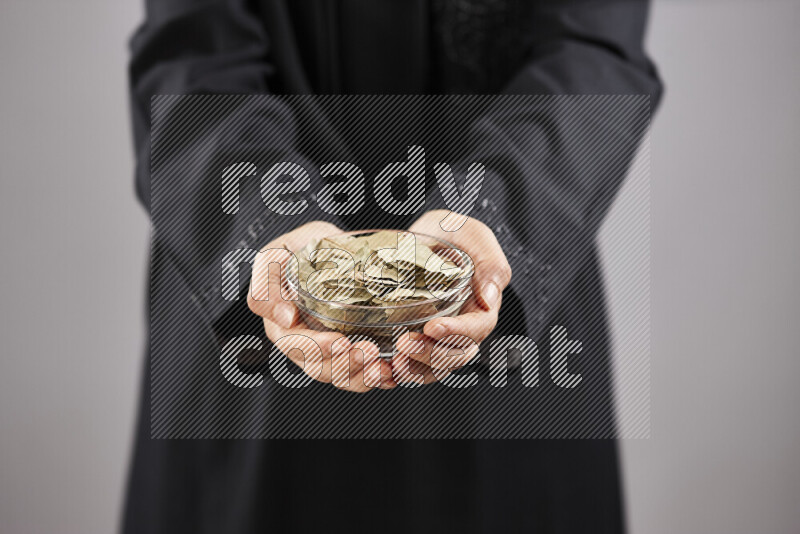 Woman in abaya holding different kinds of spices in different positions