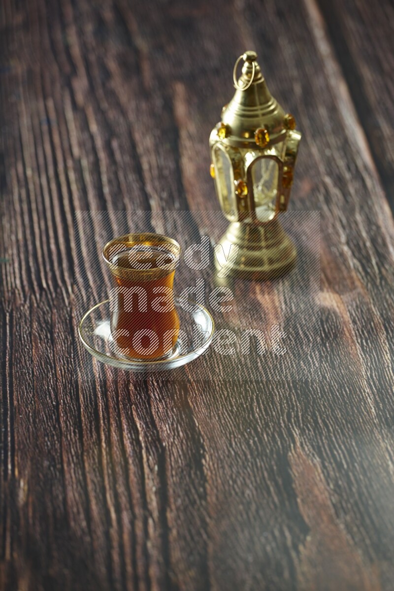 A golden lantern with different drinks, dates, nuts, prayer beads and quran on brown wooden background