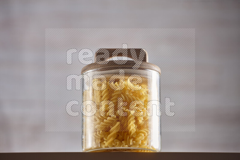 Raw pasta in glass jars on beige background